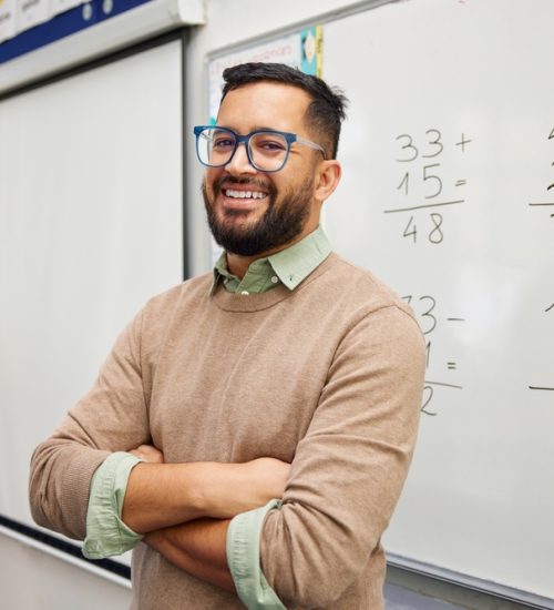 Happy,Teacher,Explaining,Mathematics,At,Whiteboard,In,Classroom.,Portrait,Of